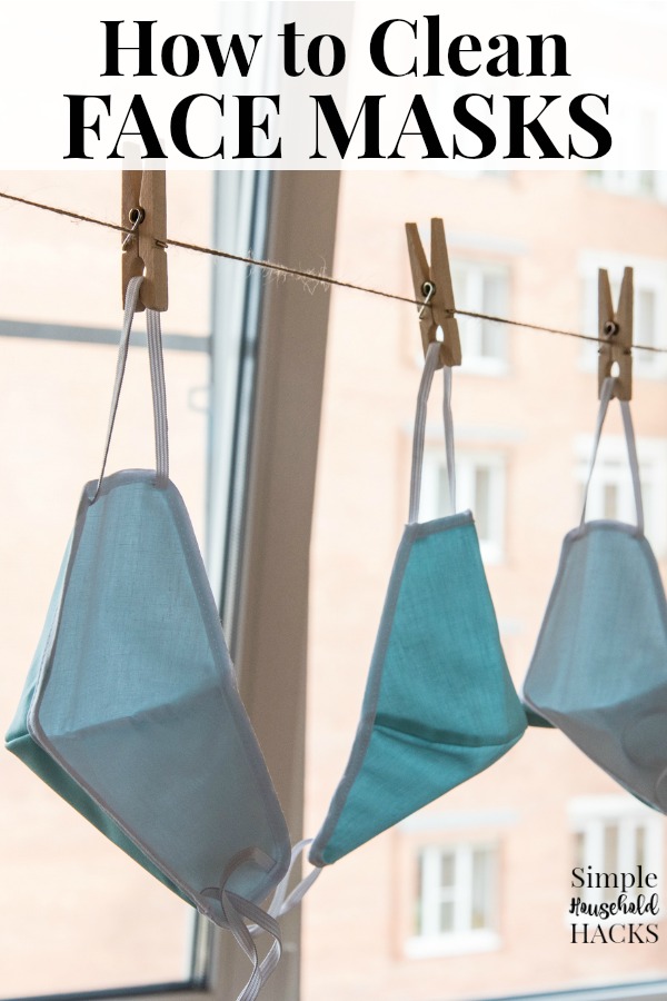 cloth face masks hanging by clothes pins from a laundry line to dry